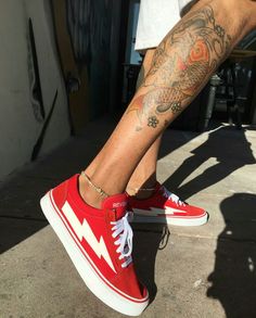 a man's legs with tattoos and red shoes