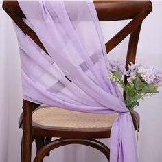 a chair with a purple sash draped over it and flowers on the back of it