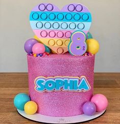 there is a pink birthday cake with lots of decorations on it and the name sophia