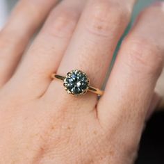 a woman's hand with a ring on it that has a blue diamond in the center