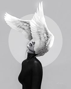 a black and white photo of a woman with wings on her head, looking up at the sky