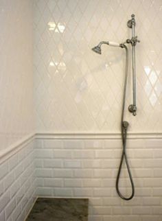 a shower head in the corner of a bathroom with white tiles on the walls and floor