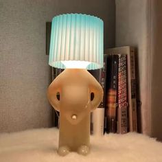 an elephant lamp sitting on top of a white fluffy floor next to a bookshelf