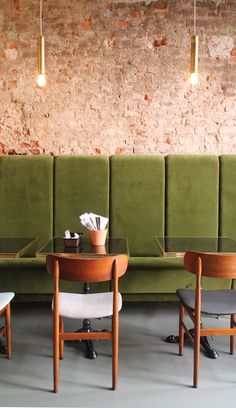 two green couches sitting next to each other in front of a table and chairs