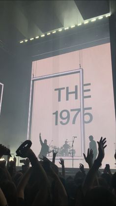 the 1970 concert is taking place in front of a large screen with their hands up