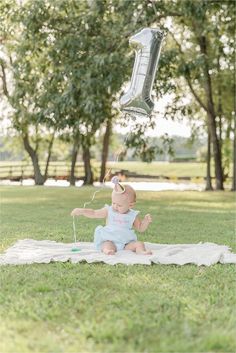 a baby sitting on a blanket with a balloon in the air