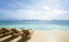 two lounge chairs sitting on top of a sandy beach