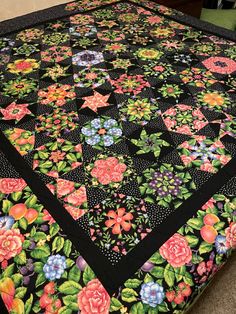 a black quilt with pink and blue flowers on it