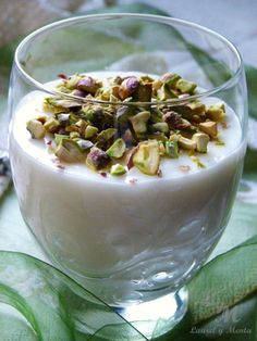 a dessert in a glass bowl with nuts on top