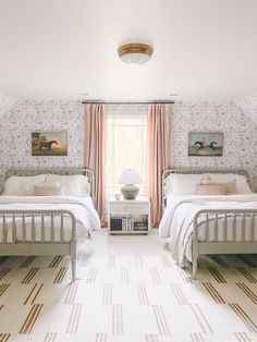 two twin beds in a bedroom with floral wallpaper and striped rugs on the floor