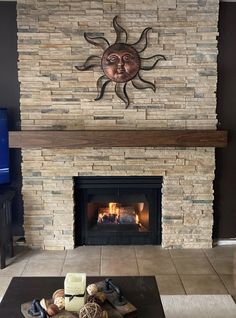 a living room with a stone fireplace and sun decoration on the wall above it's mantle