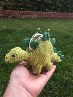 a small crocheted dinosaur keychain in someone's hand