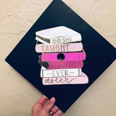 a hand holding up a graduation cap decorated with books and the words and she taught