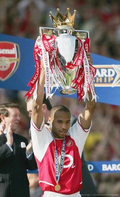 a man holding up a trophy while wearing a red and white uniform on top of his head