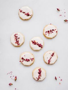 several cookies with white frosting and red flowers on them