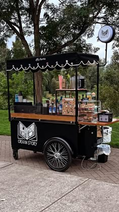 an old fashioned ice cream cart is parked on the side of the road in front of a tree