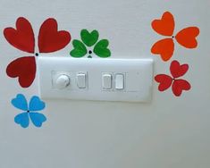 a white light switch with red, green and blue flowers painted on it's side