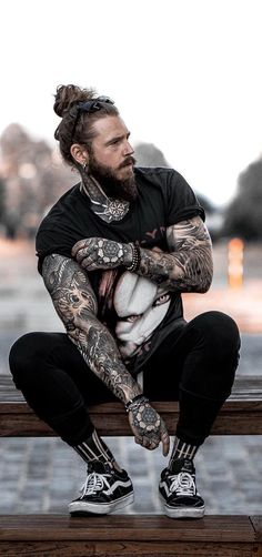 a man with tattoos sitting on a bench