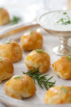 small appetizers are arranged on a plate with dipping sauce in the bowl behind them