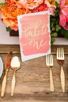 the table is set with gold utensils and flowers