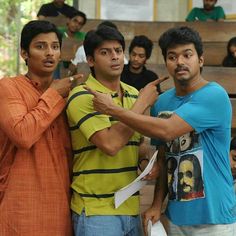 three young men standing next to each other in front of a group of people, one pointing at something