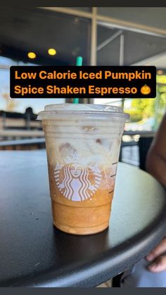 a cup of coffee sitting on top of a table with the words low calorie iced pumpkin spice shaker espresso