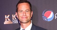 a man in a suit and tie posing for a photo on the red carpet at an event