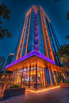 A city hotel exterior with bold neon lighting illuminating the building’s sleek lines against the night sky.