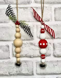 two christmas ornaments hanging on a brick wall next to a red and white striped ribbon