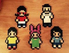 four pixelated characters are displayed on a wooden surface, each with different colors and sizes