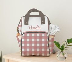 a pink and white backpack sitting on top of a table next to a potted plant