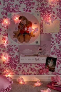 there is a pink wall with pictures and lights on it in the room that has been decorated