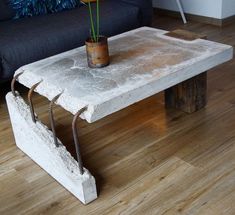 a concrete table with a potted plant on it and a black couch in the background