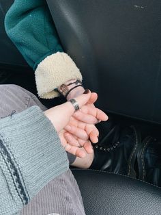 two people holding hands in the back seat of a car, one with a ring on it's finger