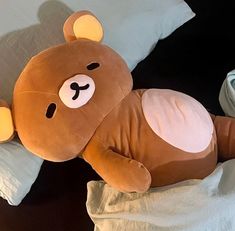 a brown teddy bear laying on top of pillows