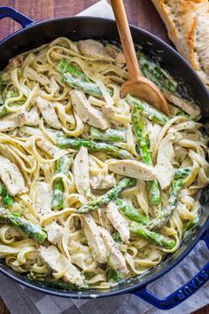 chicken and asparagus pasta in a skillet with a wooden spoon on the side