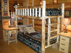 a bunk bed in a log cabin with two lamps on each side and a night stand next to it