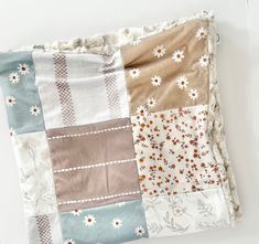 a patchwork blanket with flowers on it is laying on top of a white surface