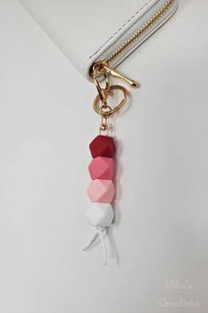 a white purse with a pink, red and white tassel hanging from it's side