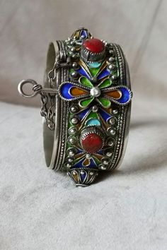 An elegant bracelet that symbolizes the Moroccan Amazigh culture. It can be worn on all occasions. It is made of silver and decorated with colorful patterns and red stones. Berber Amazigh hinged cuff bracelet in silver and enamel - Morocco - Inner diameter: 6 cm - Total weight: 72.4 grams If you have any questions about this item, please feel free to contact me. I will be happy to respond as soon as possible. Visit my shop: yourarticles Artisan Bangle As Festival Gift, Artisan Bangle For Festivals As A Gift, Artisan Bangle For Festivals And Gifts, Artisan Bangle As Gift For Festivals, Artisan Bangle As A Gift For Festivals, Traditional Inlay Cuff Bangle Bracelet, Unique Metal Bracelets For Festivals, Unique Bracelets With Intricate Design For Festivals, Bohemian Engraved Bracelets As Gift