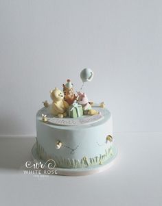 there is a cake that has animals on top and balloons in the air above it