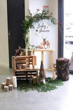 a baby shower sign sitting on top of a wooden bench next to candles and trees