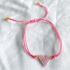 Pink heart seed bead bracelet. Features adjustable silk cord. Heart measures about 3/4” wide. Perfect for ages 4 and up. Gold details. Comes in linen travel pouch. Made with love in Asia. Heart Seed Bead, Sparkle Bracelet, Sister Bracelet, Leather Bangle, Turquoise Bead Bracelet, Seed Bead Bracelet, Freshwater Pearl Bracelet, Metal Heart, Silk Cord