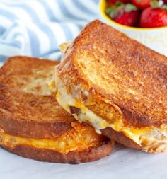 two grilled cheese sandwiches with strawberries in the background