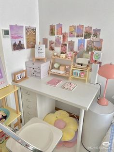 a white desk topped with lots of pictures and furniture next to a lamp on top of a table