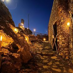 candles are lit on the rocks in front of an old stone building with stairs leading up to it