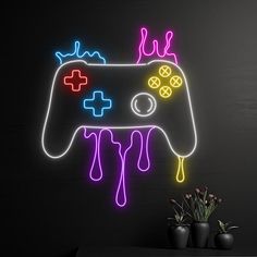 a neon gaming controller is on display in front of a black wall and vase with flowers