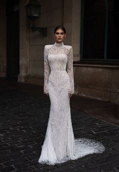 a woman in a white wedding dress standing on a cobblestone street