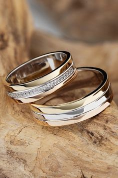 two wedding rings sitting on top of a piece of wood with diamonds in the middle