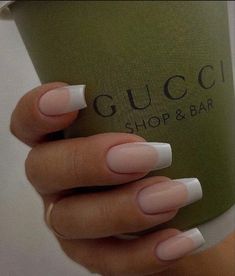 a woman's hand holding a coffee cup with white and pink acrylic nails